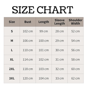 May include: A size chart table with the heading SIZE CHART. The table lists sizes S through 3XL with corresponding measurements in centimeters for bust, length, sleeve length, and shoulder width. The grid has a light beige background with black text.