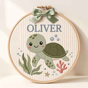 Peut inclure: Un tambour à broder en bois circulaire contenant un tissu à rayures verticales beiges. La broderie représente une tortue de mer verte, des algues vertes, un corail rose, une petite étoile et des bulles bleues. Le nom OLIVER est brodé en bleu.