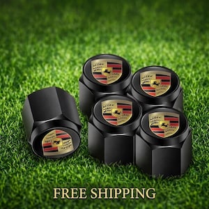 May include: A set of five black hexagonal tire valve caps, each featuring a circular emblem with the Porsche crest in red, black, and gold colors. The crest displays a central horse and horizontal stripes, providing a distinct automotive accessory.