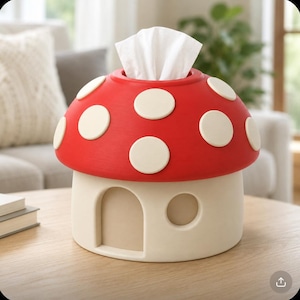 Peut inclure: Un distributeur de mouchoirs en forme de champignon avec un chapeau rouge vif orné de pois blancs. La base est un cylindre de couleur crème conçu pour ressembler à une petite maison, avec une porte arquée en retrait et une fenêtre ronde.