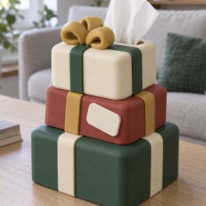 Könnte beinhalten: Ein rechteckiger Taschentuchbox-Überzug, der wie ein Stapel aus drei verpackten Geschenken aussieht. Die oberste Box ist cremefarben mit einem dunkelgrünen Band und einer senfgelben Schleife. Die mittlere Box ist rot mit einem senfgelben Band. Die untere Box ist dunkelgrün mit einem cremefarbenen Band.
