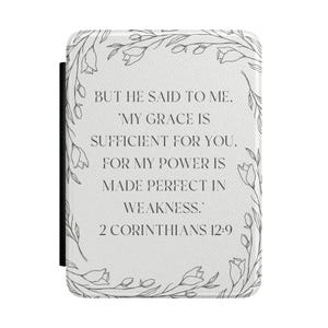 May include: A white rectangular e-reader case featuring a delicate gray line-art floral border. The center text reads: BUT HE SAID TO ME, 'MY GRACE IS SUFFICIENT FOR YOU, FOR MY POWER IS MADE PERFECT IN WEAKNESS.' 2 CORINTHIANS 12:9 in a dark gray font.