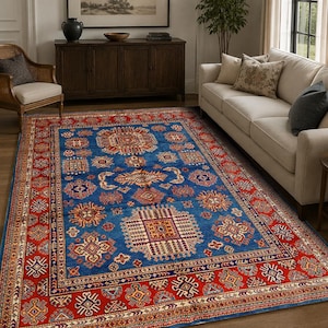 May include: A rectangular area rug featuring a vibrant blue central field adorned with intricate geometric patterns in shades of red, cream, and navy. The rug is framed by a wide, ornate red border filled with repeating tribal-inspired motifs.