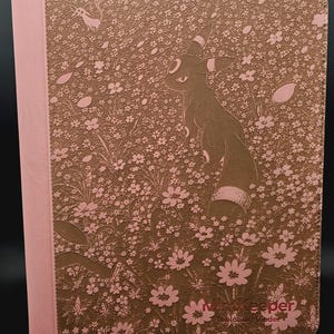 May include: A rectangular binder with a pink spine and a brown cover featuring a textured pattern of small pink flowers and leaves. The cover displays a silhouette of the character Umbreon and the text "MiniKeeper Toploader Binder" in the corner.