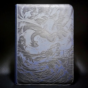 May include: A rectangular protective case featuring a debossed graphic of a large dragon flying over a boat on turbulent ocean waves. The case is coloured in shades of dark grey and blue with a textured surface and stitched edges along the perimeter.