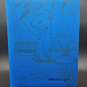May include: A bright blue zipped binder featuring a debossed illustration of a Lapras creature with a person sitting on its back on a beach. The scene includes palm leaves, clouds, and the ocean. The word MintKeeper is printed in the bottom right.