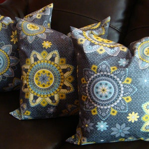 May include: Three decorative throw pillows with a gray background and a yellow, blue, and white mandala pattern.