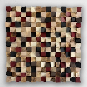 May include: A square wall art piece composed of numerous small, individual wooden blocks arranged in a grid. The blocks feature varying depths and are finished in a palette of natural wood grain, deep red, matte black, and light cream colors.