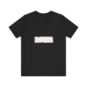 May include: A black short-sleeved t-shirt featuring a rectangular graphic on the chest. The graphic contains the white text NO ONE STARTS A BAG OF BAGS in a bold, serif font with a slightly distressed or blurred edge effect on the lettering.