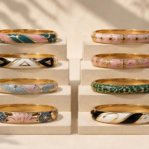 Peut inclure: Huit bracelets rigides en métal doré disposés en deux colonnes. Les bracelets présentent divers motifs en émail, notamment des tourbillons roses et bleu sarcelle, des motifs géométriques noirs et blancs, des fleurs et des détails filigranés.