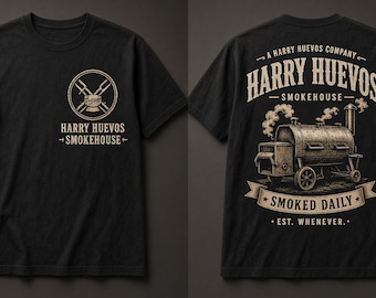 Puede incluir: Una camiseta negra de manga corta con un logotipo frontal de utensilios cruzados y el texto Harry Huevos Smokehouse. La parte posterior muestra un gráfico grande de un ahumador con humo, el texto Harry Huevos Smokehouse y Smoked Daily.