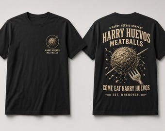 Puede incluir: Una camiseta negra de manga corta con un pequeño gráfico en el pecho izquierdo y un gráfico grande en la espalda. El frente muestra una albóndiga con un tenedor y el texto Harry Huevos Meatballs. La espalda presenta una versión más grande de la albóndiga con tenedor, el texto A Harry Huevos Company, Harry Huevos Meatballs, Come Eat Harry Huevos y Est. Whenever.