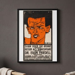 May include: A framed poster featuring a stylised orange illustration of a person's face with black hair and outlines. Below the image, black text reads: SHAW ODER DIE IRONIE, BESSER ALS SHAKESPEARE, DR. EGON FRIEDELL, and event details.