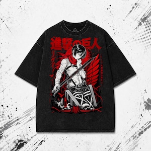 May include: A black short-sleeve t-shirt featuring a graphic print of an anime character with short dark hair, a red scarf, and a sword. The design includes red Japanese text, a red circular background, and a red wing emblem on a black background.
