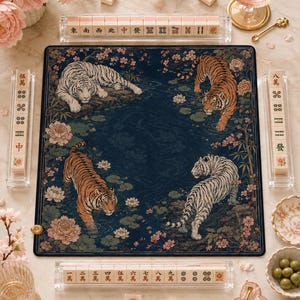 May include: A square mahjong mat featuring a dark blue background with four tigers, two orange and two white, surrounded by pink floral patterns. The mat is accompanied by four clear acrylic racks holding mahjong tiles with various Chinese characters.