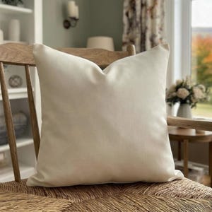 Close-up of the solid ivory pillow cover on a wooden chair with a rush seat