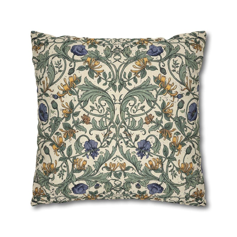 A square pillow features a detailed botanical damask pattern with blue flowers, yellow blossoms, and green vines on a cream background.