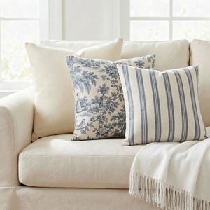 French cottage pillow cover set on an ivory sofa: solid ivory, blue toile and blue ticking stripe pillow covers