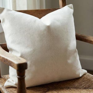 Close-up of the solid ivory pillow cover in a wooden armchair with a rush seat
