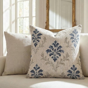Woven indigo damask tapestry pillow on a cream linen sofa in an elegant French chateau-style room