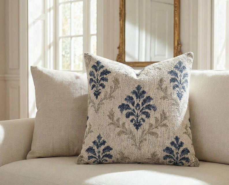 Woven indigo damask tapestry pillow on a cream linen sofa in an elegant French chateau-style room