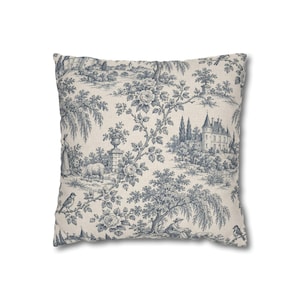 Slate blue toile de Jouy square pillow cover with chateau, trees and birds on a warm ivory background, shown on plain white.