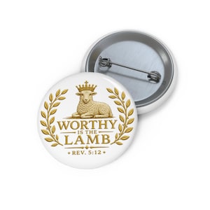 May include: A round pinback button featuring a gold-colored illustration of a lamb wearing a crown, surrounded by laurel branches. The text reads WORTHY IS THE LAMB and REV. 5:12. The back of the button shows a silver metal pin mechanism.