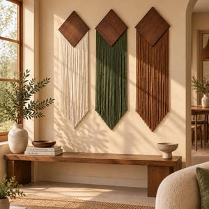 Peut inclure: Trois décorations murales composées de sommets en bois brun foncé en forme de losange avec de longs cordons droits suspendus de couleur crème, vert olive et terre cuite. Chaque pièce est montée verticalement en pointe symétrique.