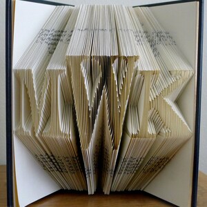 May include: A book with the word "LOVE" folded into the pages. The book is open and the pages are folded into a three-dimensional design.