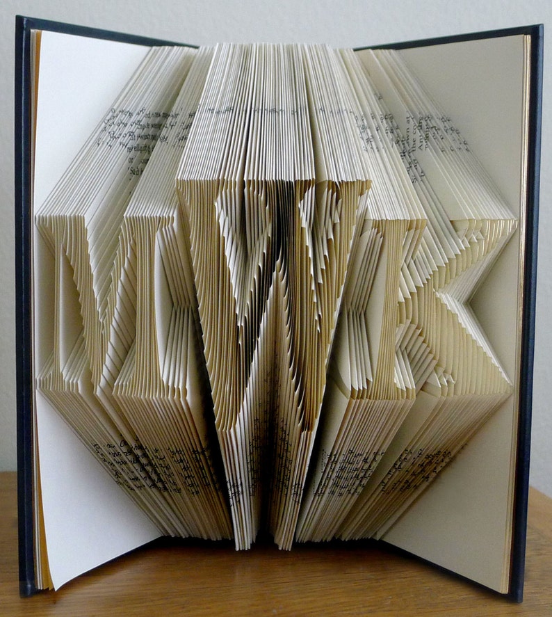 May include: A book with the word "LOVE" folded into the pages. The book is open and the pages are folded into a three-dimensional design.