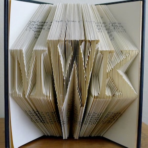 May include: A book with the word "LOVE" folded into the pages. The book is open and the pages are folded into a three-dimensional design.
