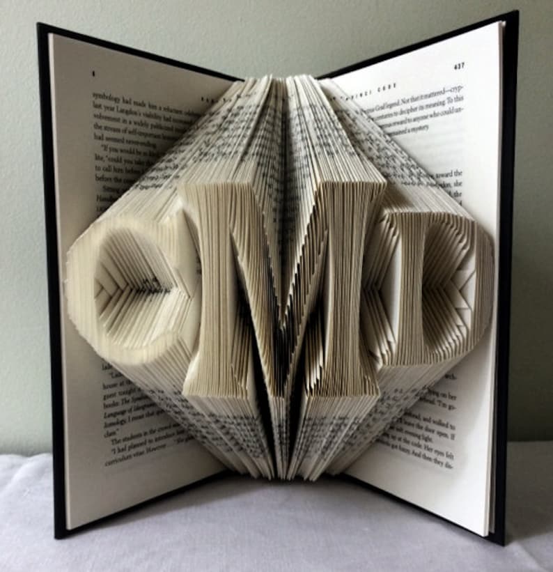 May include: A book with the letters "CMD" folded into the pages. The book is open and the pages are folded to create the letters.