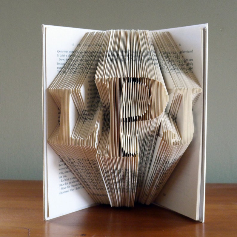 May include: A book with pages folded into the shape of the word "LOVE". The book is open and the folded pages are standing up.