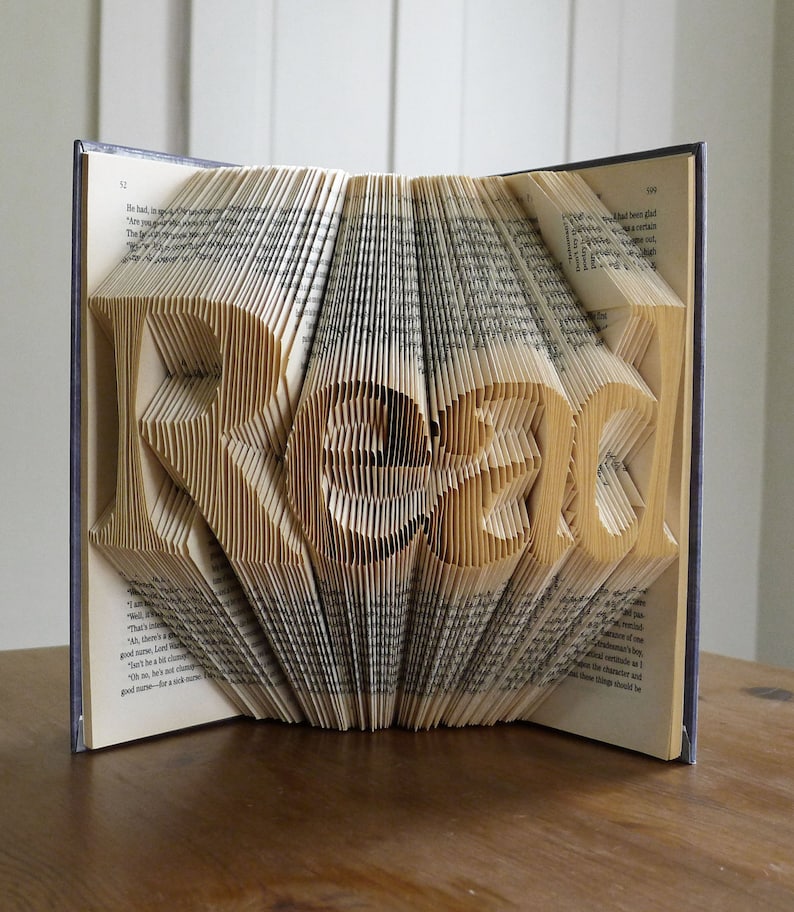 Puede incluir: Una escultura de arte de libro con la palabra "READ" doblada en las p&aacute;ginas. El libro est&aacute; abierto y las p&aacute;ginas est&aacute;n dobladas en un dise&ntilde;o tridimensional.