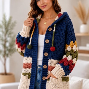 May include: A long-sleeved crochet cardigan featuring a deep blue base with horizontal stripes in cream, olive green, and terracotta. The sleeves include multi-colored granny square accents, while the front has large brown buttons and two pockets.