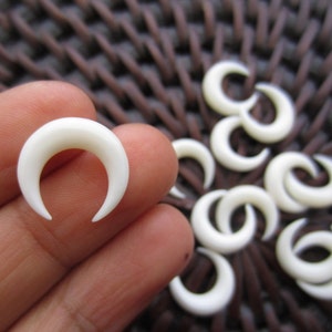 Puede incluir: Un conjunto de diez abalorios de hueso blanco en forma de media luna. Los abalorios miden aproximadamente 2,5 cm de largo y son ideales para la elaboración de joyas u otras manualidades.