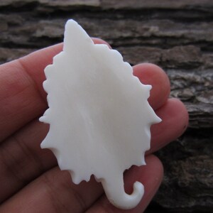 May include: White ceramic leaf pendant with a detailed, intricate design. The leaf is smooth and has a slightly textured surface.