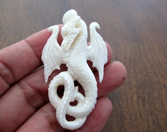 May include: A white carved dragon pendant made of bone. The dragon is curled up with its wings spread out.