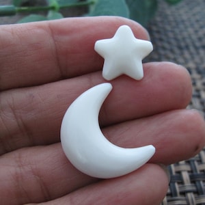 May include: Two white ceramic ornaments, a crescent moon and a five-pointed star.
