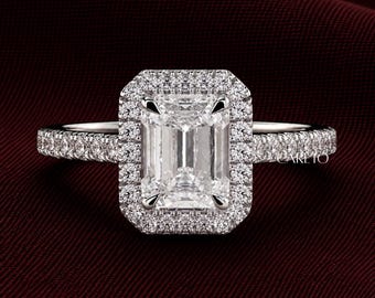 May include: A silver-toned ring featuring a large, rectangular emerald-cut center stone surrounded by a halo of small, round, brilliant-cut stones. The band is also encrusted with a row of small, round stones. The word CARETO is visible on the band.