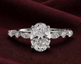 May include: A silver-toned ring featuring a large oval-cut center stone held by four prongs. The band is accented with alternating marquise-cut and round-cut stones along the sides. The word CARETO is printed in small white letters on the right side.