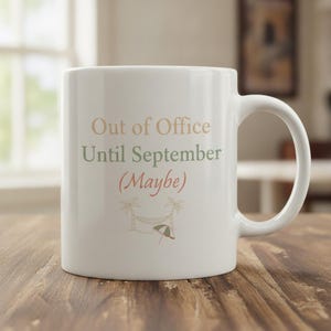 Może przedstawiać: Biały ceramiczny kubek z napisem Out of Office Until September (Maybe) w kolorach beżowym, szałwiowej zieleni i koralowym. Pod tekstem znajduje się mała graficzna ilustracja dwóch palm, hamaka i parasola plażowego w pasujących kolorach.
