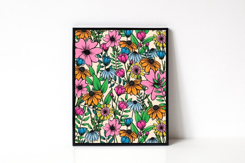 May include: A framed floral art print featuring a vibrant, colorful pattern of stylized flowers. The artwork showcases pink, orange, blue, and yellow blooms with green foliage against a cream background. The print is enclosed in a black frame.