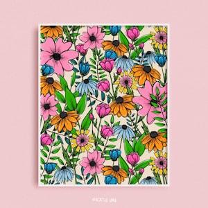 May include: A floral art print featuring a vibrant pattern of colorful flowers. The design includes pink, orange, blue, and yellow blooms with black centers and green foliage, set against a cream background. The artist's name, KATIE VAZ, is in the bottom corner.