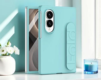 May include: A light blue protective phone case for a foldable smartphone. The case features a vertical camera cutout with two circular lenses and a raised, embossed rectangular panel on the side with the word FOLD printed in capital letters.