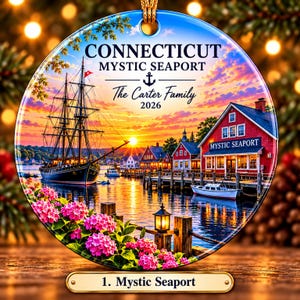 May include: A round ceramic ornament featuring a sunset scene of Mystic Seaport, Connecticut, with a tall ship, red buildings, and pink flowers. The text reads CONNECTICUT MYSTIC SEAPORT, The Carter Family, 2026, and 1. Mystic Seaport.