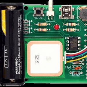 以下が含まれることがあります： ホルダーに入った2本の黒い1.5V単3電池、正方形の白いGPSモジュール、マイクロUSBポート、ADJUSTとラベル付けされた黒い押しボタン、様々な抵抗器、コンデンサ、配線付きの集積回路を備えた緑色のプリント基板。