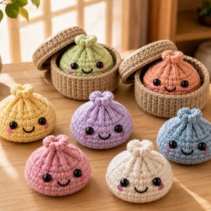 Op de afbeelding: Een verzameling van zeven gehaakte knoedelspeeltjes in diverse pastelkleuren, waaronder geel, lichtgroen, perzik, lavendel, roze, wit en blauw. Elke knoedel heeft een lachend gezichtje met zwarte ogen en roze wangen, met twee in mandjes.
