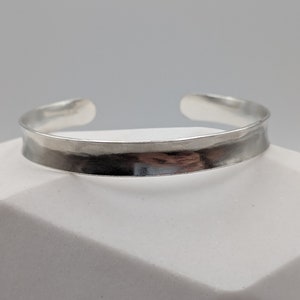 May include: A silver hammered bangle bracelet with a smooth, polished finish.