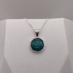 Peut inclure: Un collier en argent avec un pendentif rond en pierre bleu clair.